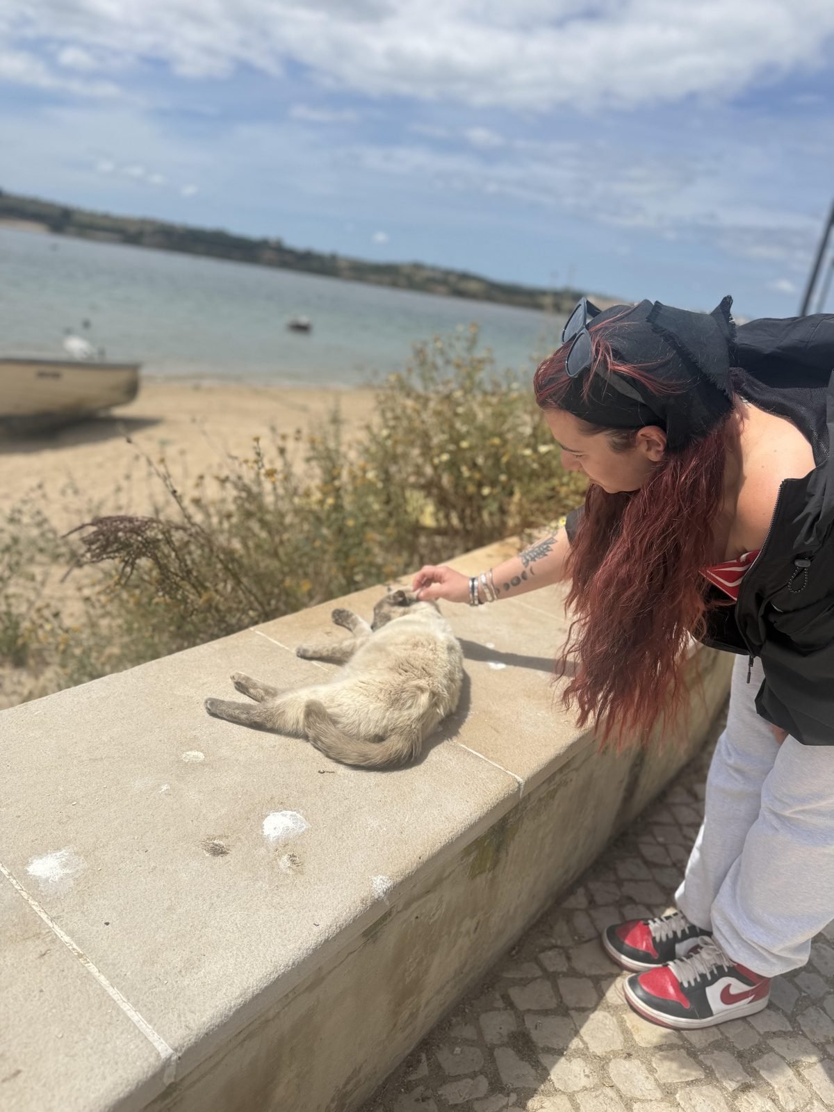 Tati crouched down, gently greeting an animal in Alvor
